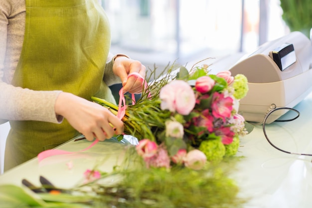 Foto concetto di persone, affari, vendita e floristica - primo piano di donna fiorista che fa mazzo al negozio di fiori