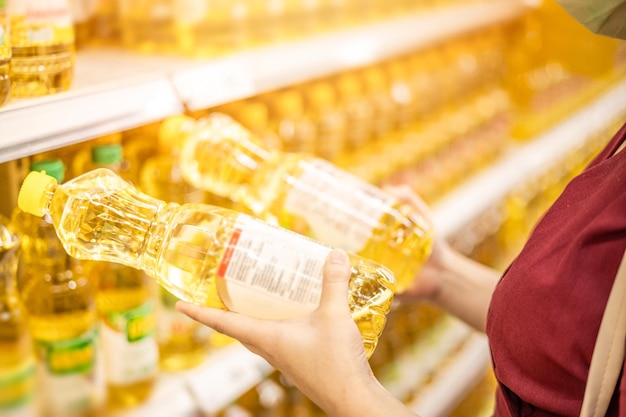 Le persone che acquistano oli da cucina per il confronto alimentare e la lettura dell'etichetta nutrizionale dei prodotti nel supermercato