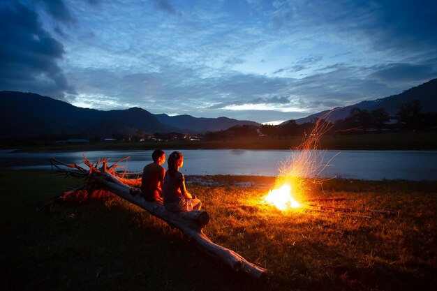 People by lake against sky during sunset