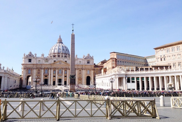 People by obelisk at st peter square with basilica against sky