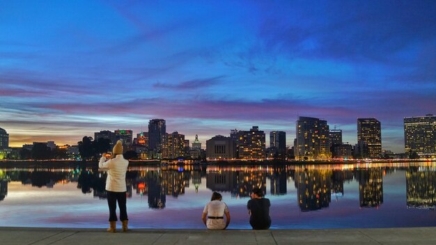 People by river against cityscape