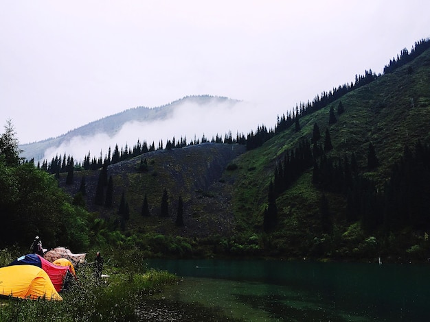 people camping by river against sky