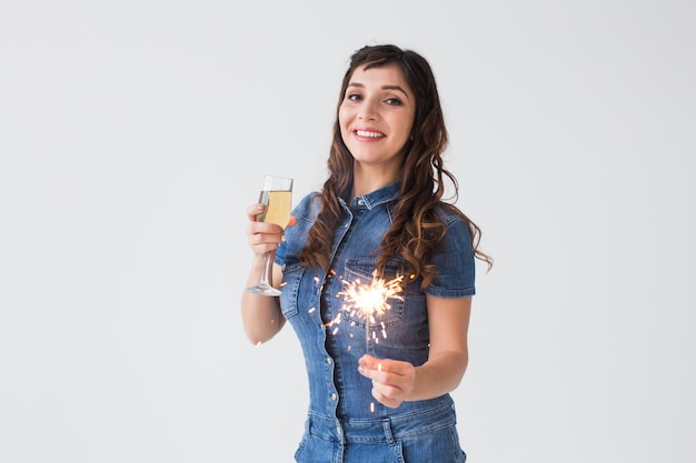 People, celebration and holiday concept - Lovely woman with sparkler and glass of champagne over white background with copy space