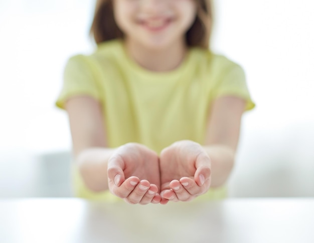 people, charity, childhood and advertisement concept - close up of child cupped hands at home