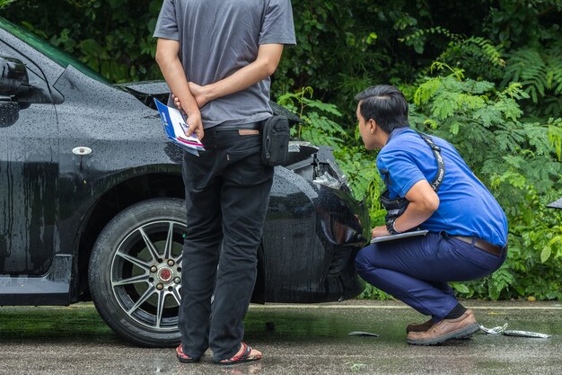 事故で怪我をした黒い車の前をチェックしている人