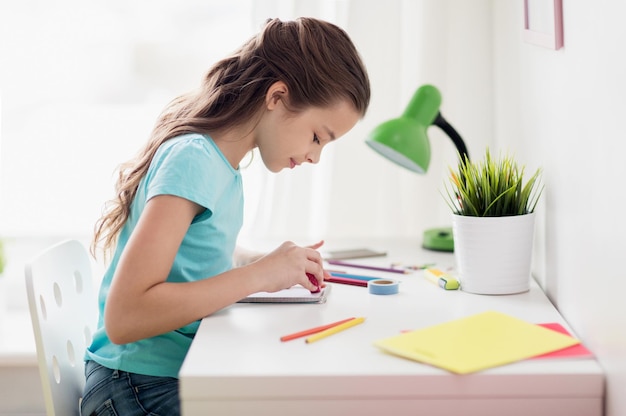 Photo people, children, creativity and art concept - happy girl drawing at home