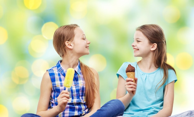 사람, 어린이, 친구 및 우정 개념 - 녹색 휴일 조명 배경 위에 아이스크림을 먹는 행복한 어린 소녀