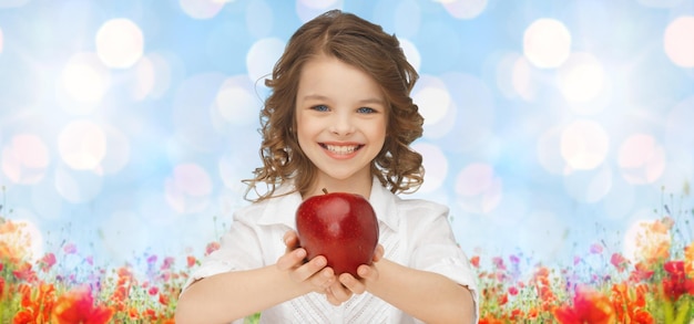 люди, дети, здоровое питание, лето и концепция еды - счастливая девушка держит красное яблоко над голубым небом и полем маков на фоне