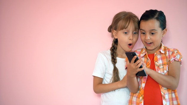 people, children, technology, friends and friendship concept - happy little girls with smartphones lying on floor at home