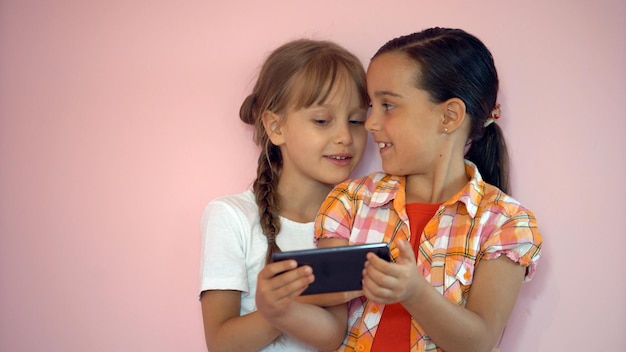 people, children, technology, friends and friendship concept - happy little girls with smartphones lying on floor at home