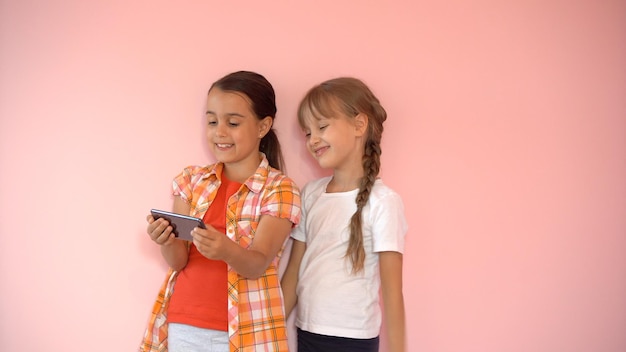 people, children, technology, friends and friendship concept - happy little girls with smartphones sitting on sofa at home