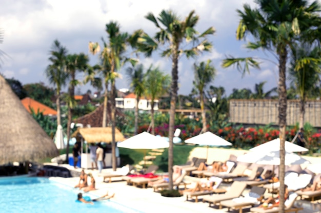 People chilling closed to swimming pool under the palms. Vacation concept.