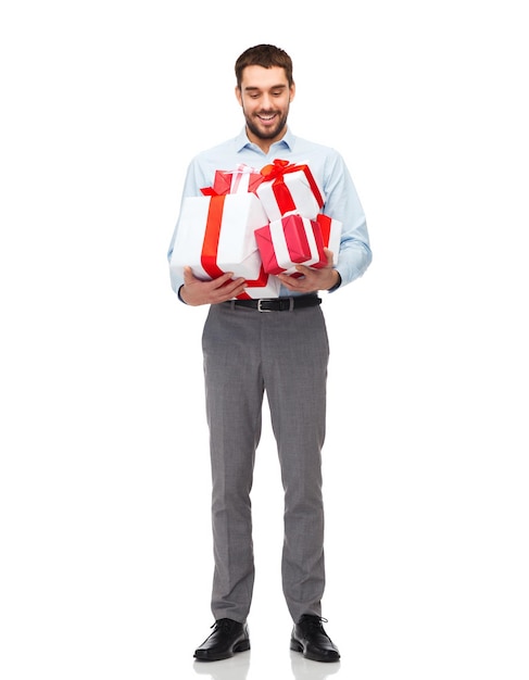 people, christmas, birthday and holidays concept - happy young man holding gift boxes