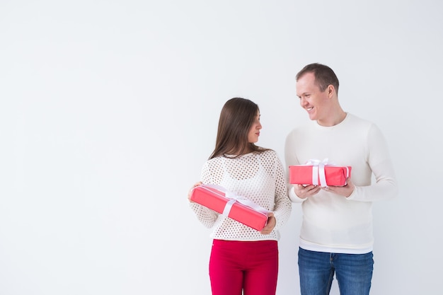 Foto persone, natale, compleanno, vacanze e concetto di san valentino - felice giovane uomo e donna con scatole regalo su sfondo bianco con spazio di copia.