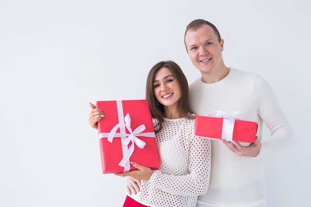 Persone, natale, compleanno, vacanze e concetto di san valentino - felice giovane uomo e donna con scatole regalo su sfondo bianco con spazio di copia.