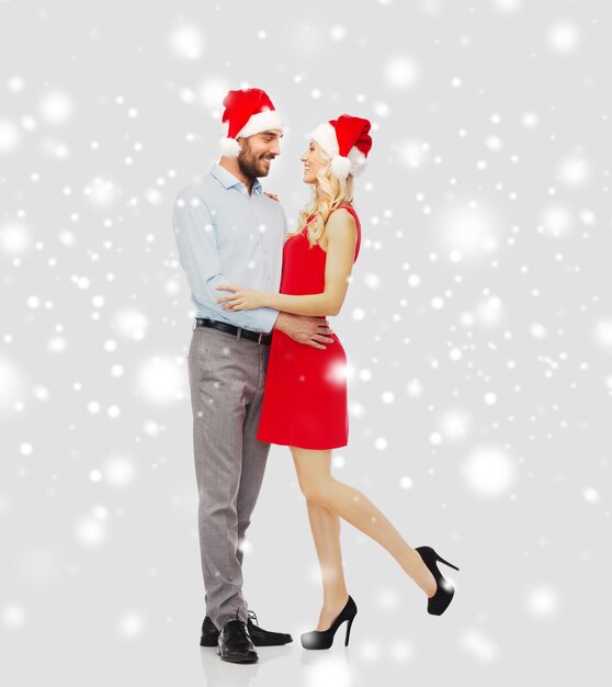 사람, 크리스마스, 사랑, 커플, 휴일 개념 - 산타 모자를 껴안고 있는 행복한 젊은 여성과 남자