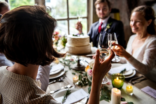 La gente aderisce ai vetri di vino sul ricevimento nuziale con la sposa e lo sposo