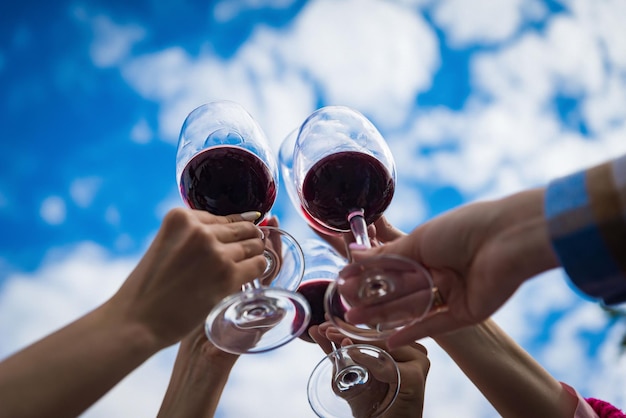 People clinking glasses with wine on the summer terrace of cafe or restaurant