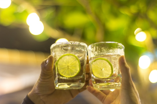 Photo people clinking with gin tonic and lime sliced in glasses.