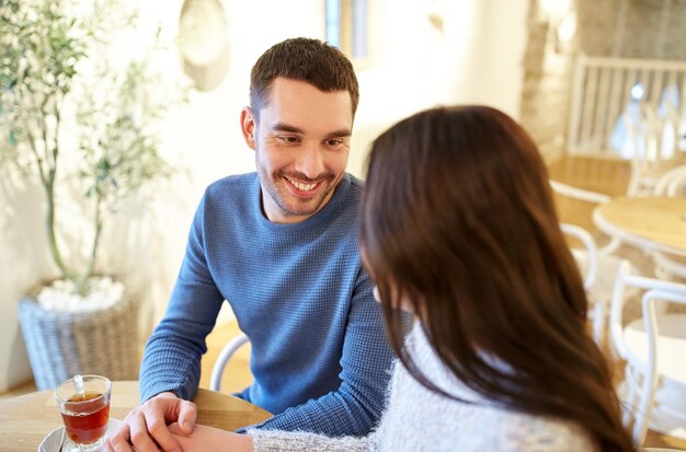 Photo people, communication and dating concept - happy couple drinking tea at cafe or restaurant