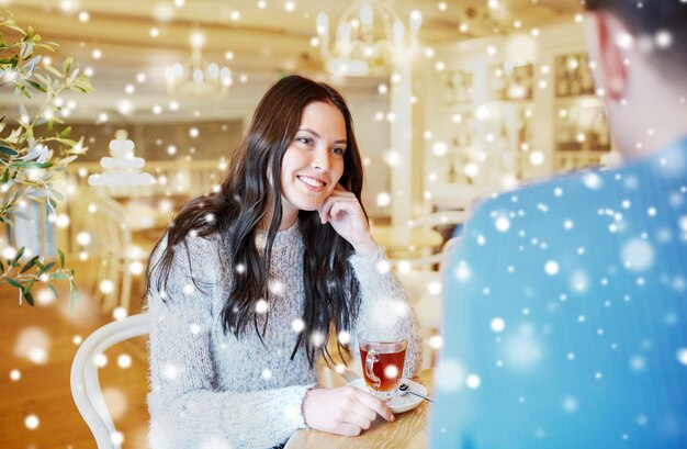 people, communication and dating concept - happy couple drinking tea at cafe or restaurant