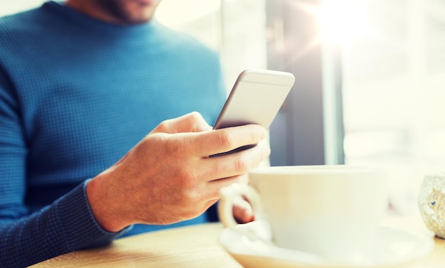 People, communication and technology concept - close up of man with smartphones at cafe