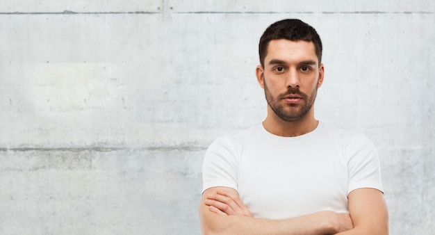 people concept - young man with crossed arms over gray stone wall background