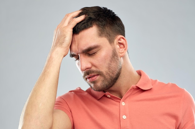 people, crisis, emotions and stress concept - unhappy man suffering from head ache over gray background