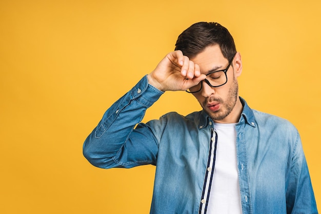 People crisis emotions and stress concept unhappy tired man suffering from head ache at home isolated over yellow background