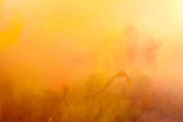 Foto persone che ballano durante il colorato holi festival sfondo multicolore sfocato del tramonto soleggiato