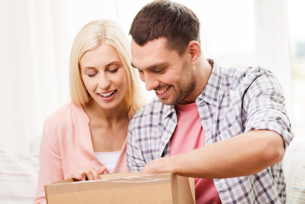 人、配達、配送、郵便サービスのコンセプト-自宅で段ボール箱や小包を開く幸せなカップル