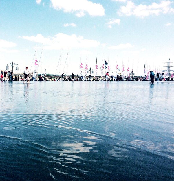 Photo people in distance with reflection of clouds in water