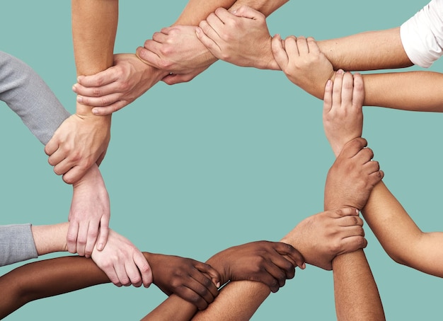 人々の多様性と、スタジオの背景に対する信頼のためのチームワークコラボレーションで手を取り合う コミュニティまたはモックアップのサークルでの合意のために団結または連帯で手を握る多様なグループ