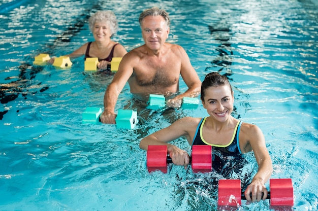 People doing exercise with aqua dumbbells in a swimming pool