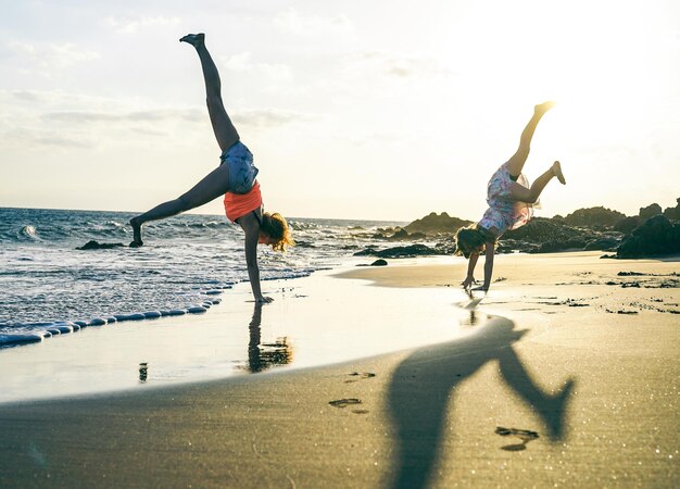 People doing handstand at beach against sky