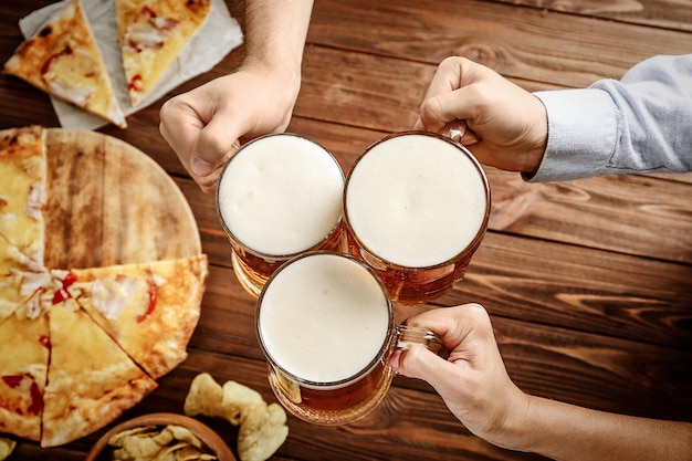 People drinking beer and eating pizza in pub