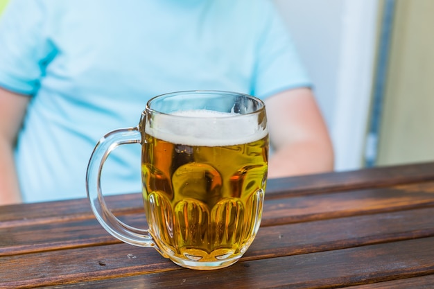 Persone, bevande, alcol, gesto e concetto di tempo libero - chiuda in su del giovane che beve birra.