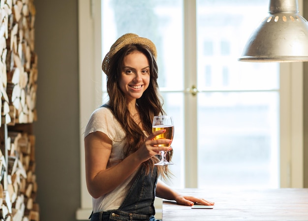 人、飲み物、アルコール、レジャーのコンセプト – バーやパブでビールを飲む幸せな若い赤毛の女性