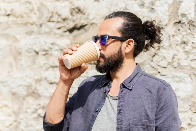 people, drinks, leisure and lifestyle - man drinking coffee from disposable paper cup on city street