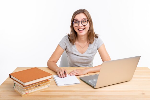 People and education concept - Happy female student sitting at the wooden table with laptop