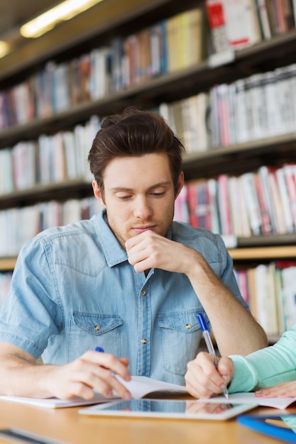 Foto concetto di persone, istruzione, tecnologia e scuola - studente maschio con rete di computer tablet pc in biblioteca