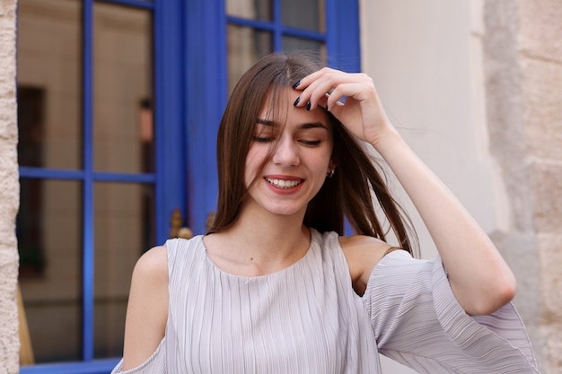 People, emotions, natural, beauty and lifestyle concept - Young beautiful cheerful woman walking on old street at tropical town. Pretty girl looking at you and smiling