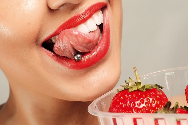 People, emotions, natural, food, beauty and lifestyle concept - Sexy Woman Eating Strawberry. Sensual Lips. Manicure and Lipstick. Desire. Beauty Girl Sexy Lips with Strawberry. white teeth