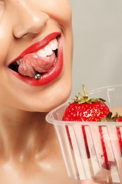 Люди, эмоции, естественные, еда, красота и образ жизни концепция - сексуальная женщина ест клубнику. Чувственные губы. Маникюр и помада. Желание. Сексуальные губы девушки красоты с клубникой. белые зубы