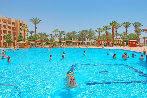 Люди наслаждаются отдыхом в тропическом курорте в бассейне в Египте Бассейн с светло-голубой водой