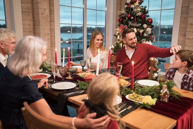 写真 お祝いのクリスマスディナーを楽しむ人々