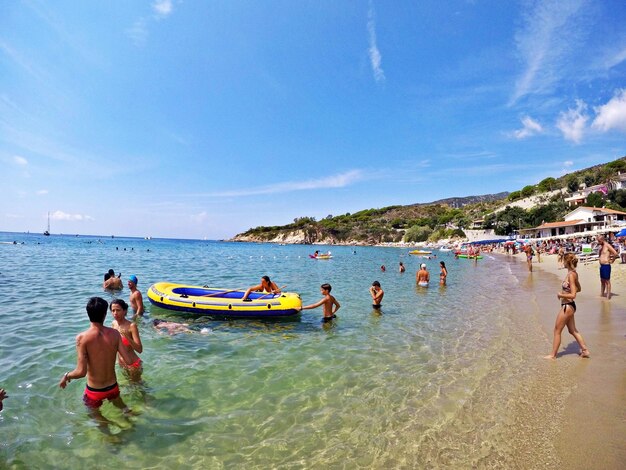 People enjoying at beach against sky