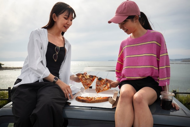 Foto persone che si godono la pizza insieme all'aperto