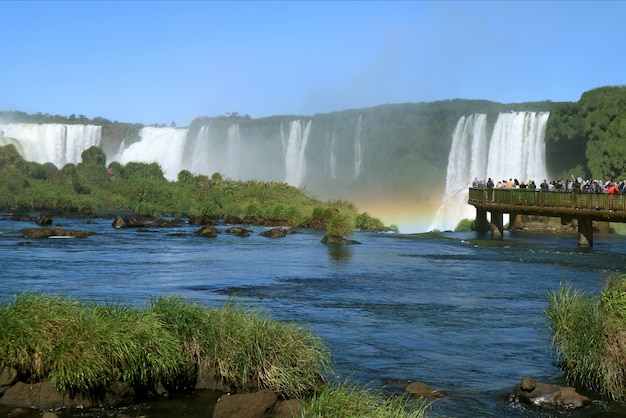 People Exploring the Powerful Iguazu Falls with a gorgeous rainbow from the Boardwalk, Brazil