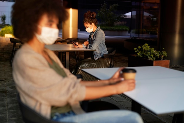 Photo people in face mask sitting alone in a cafe outdoors